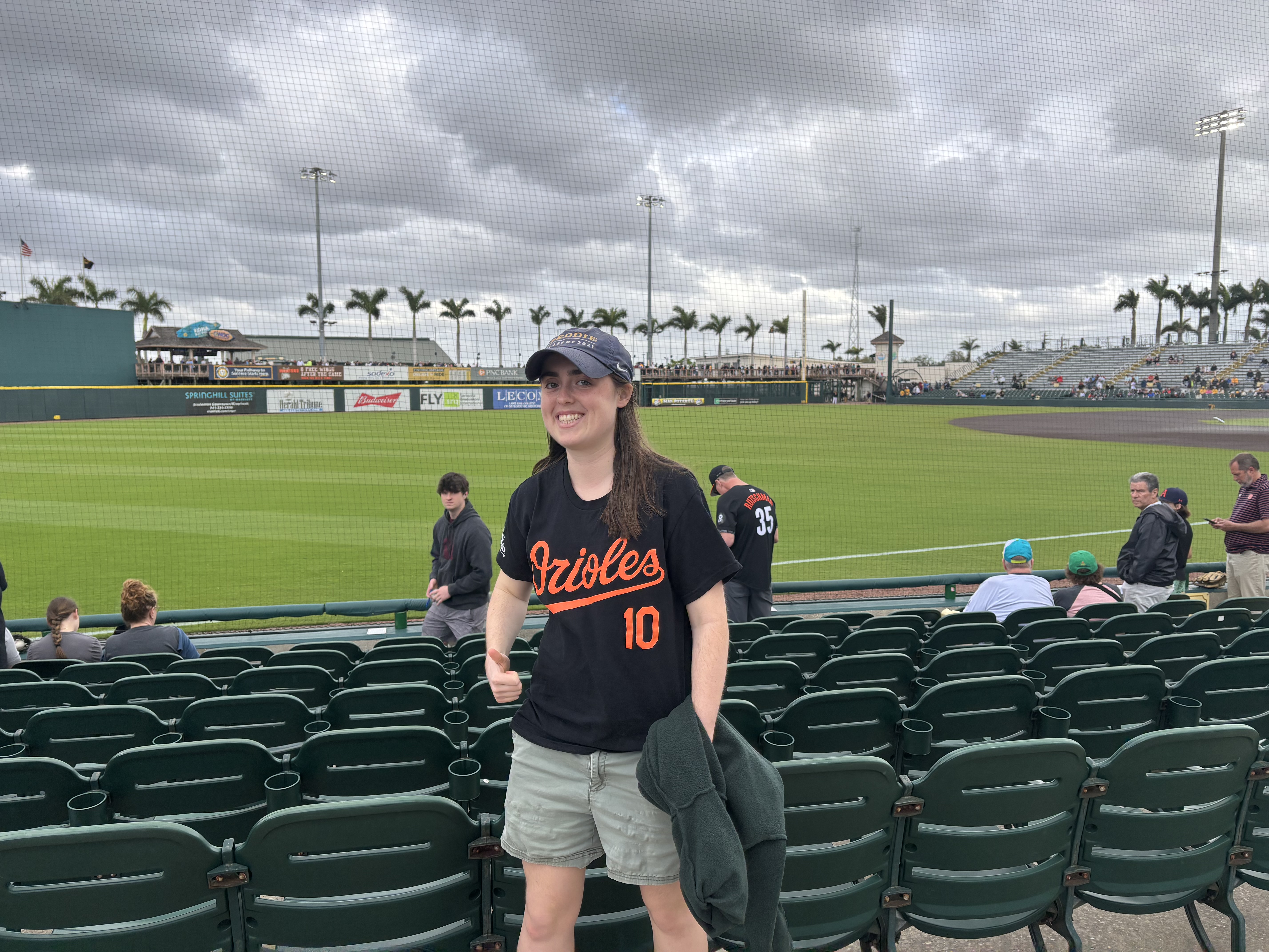 a young woman wearing an Orioles baseball jersey and hat in front of a baseball stadium