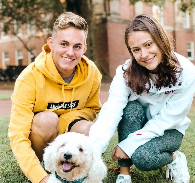 two student pose for picture with cute dog
