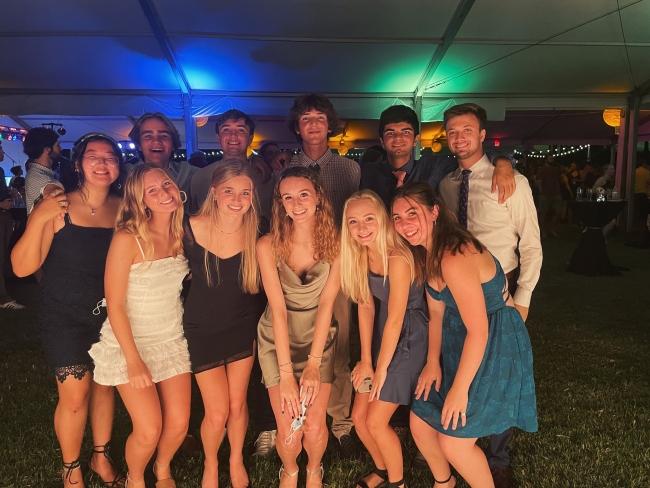 a group of students stand together and smile in front of a white tent with green and blue lights
