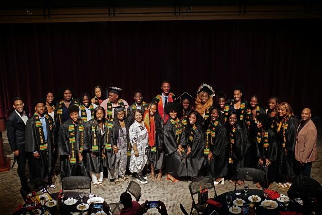 a group of Black students in graduation regalia smiling together