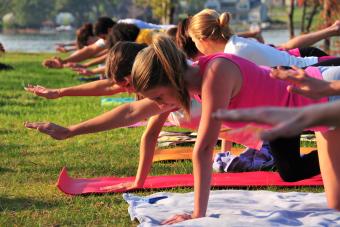 Students take yoga positions on mats laid out on the grass of Lake Campus