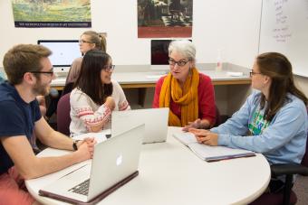 Prof. Munger sits at a round table with three students in her lab