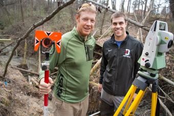 Prof. Brad Johnson and student stand in field with research equipment  