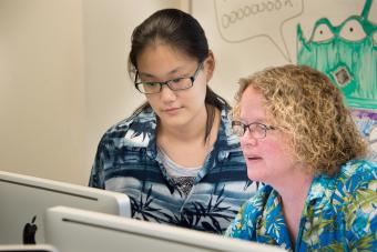 Prof. Heyer and a student look at data on a desktop computer in a lab