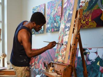 Student is painting a canvas in his studio at the Visual Arts Center