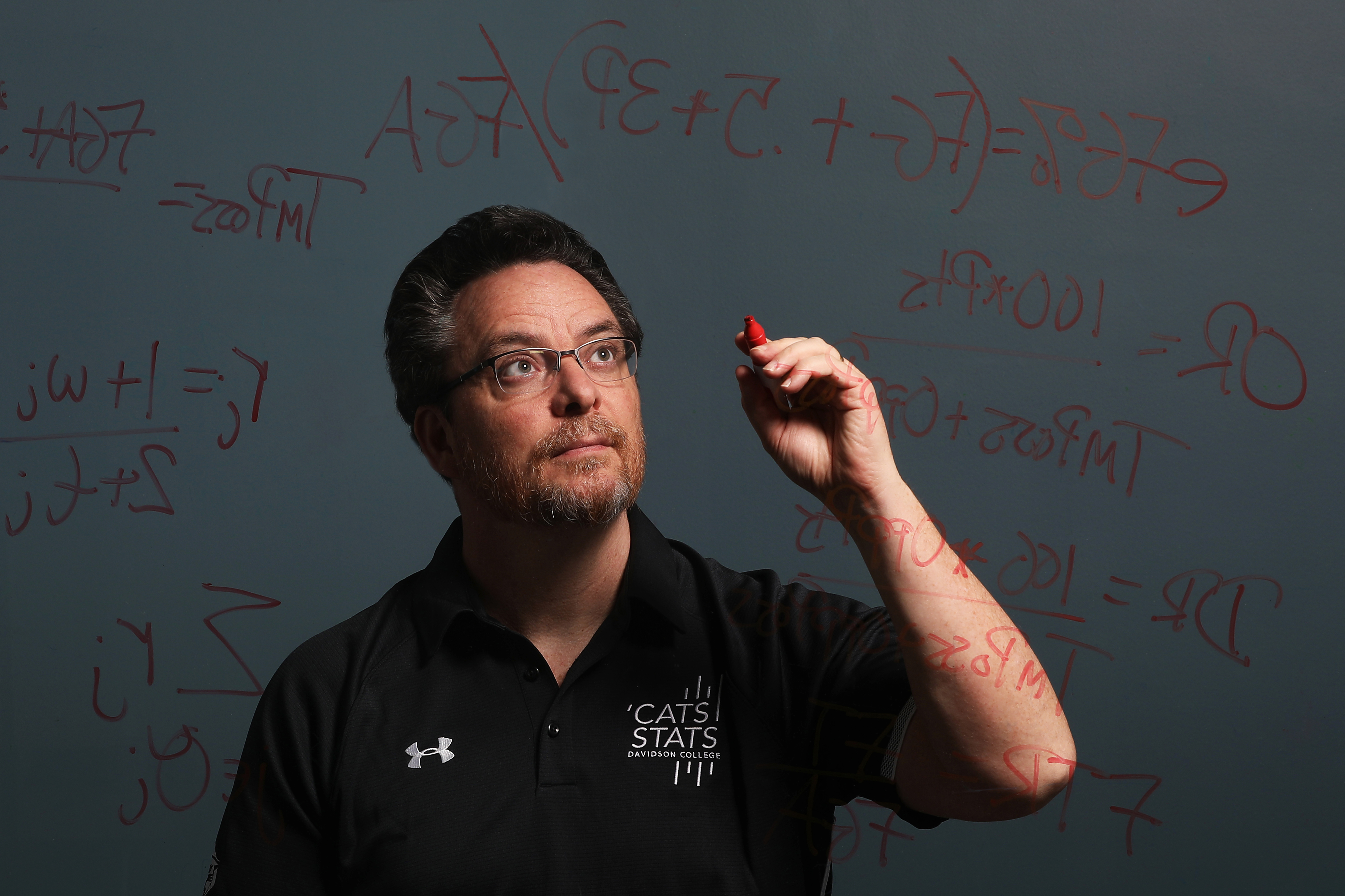 Tim Chartier writes math equations on a glass board