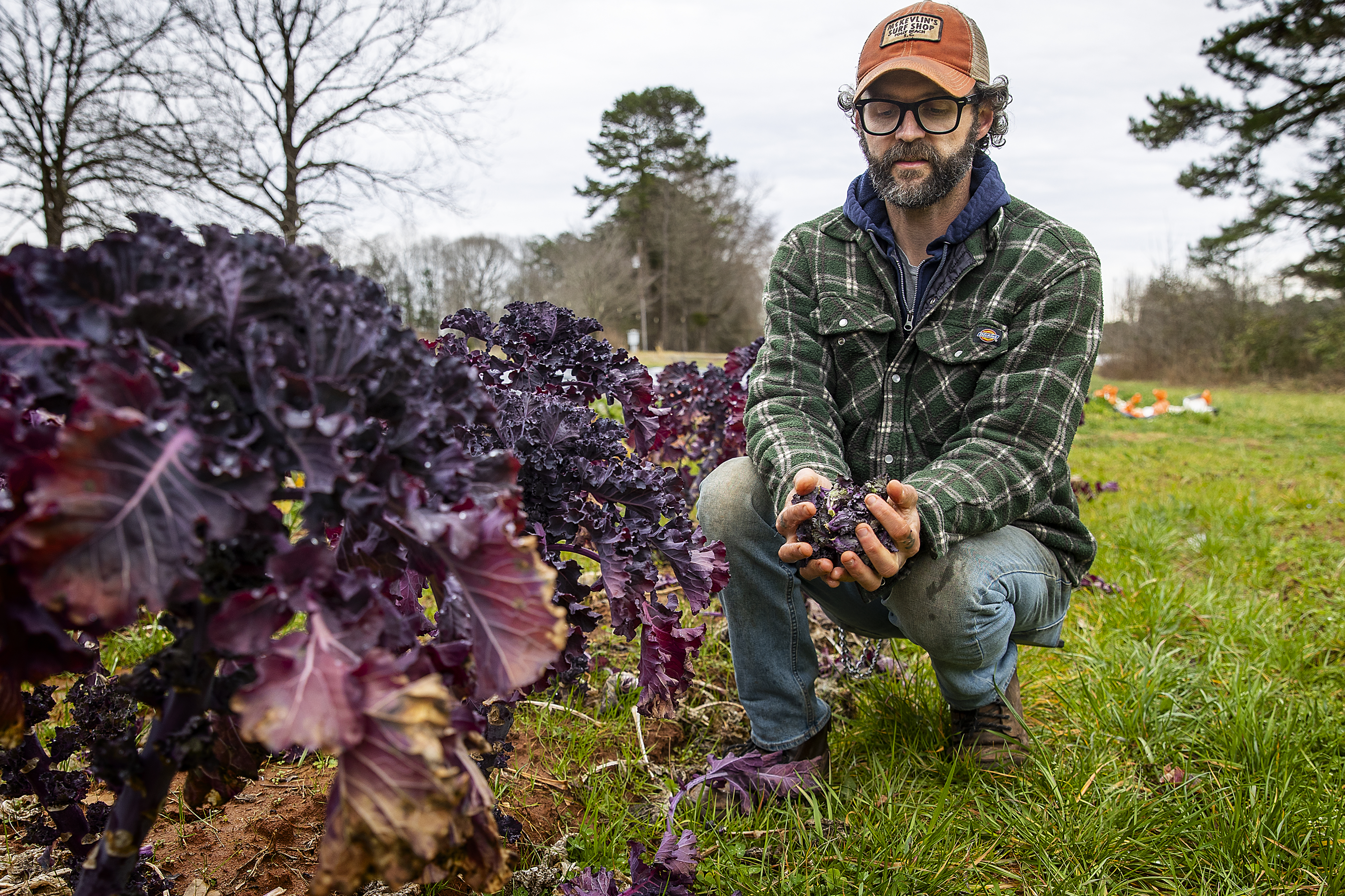 Joe Rowland kneels with Produce at Davidson College Farm