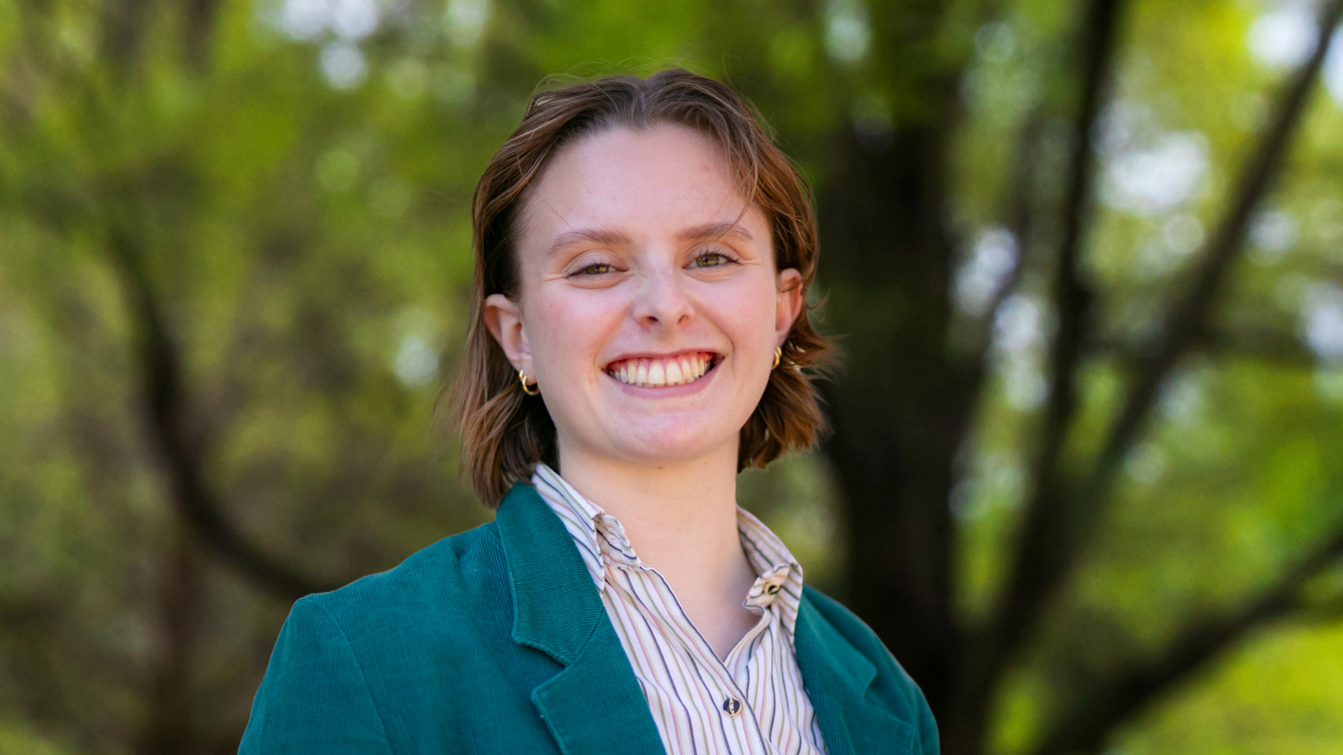 a young white woman wearing a collared shirt and jacket smiles