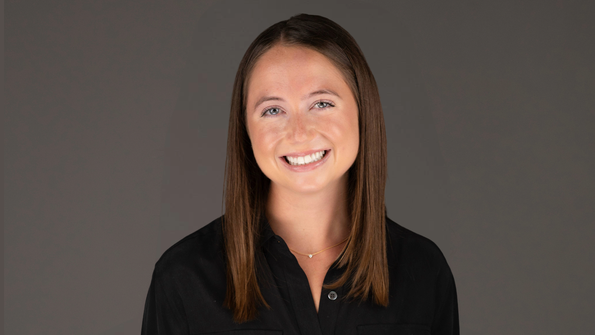 a young white woman smiling while wearing a black collared shirt