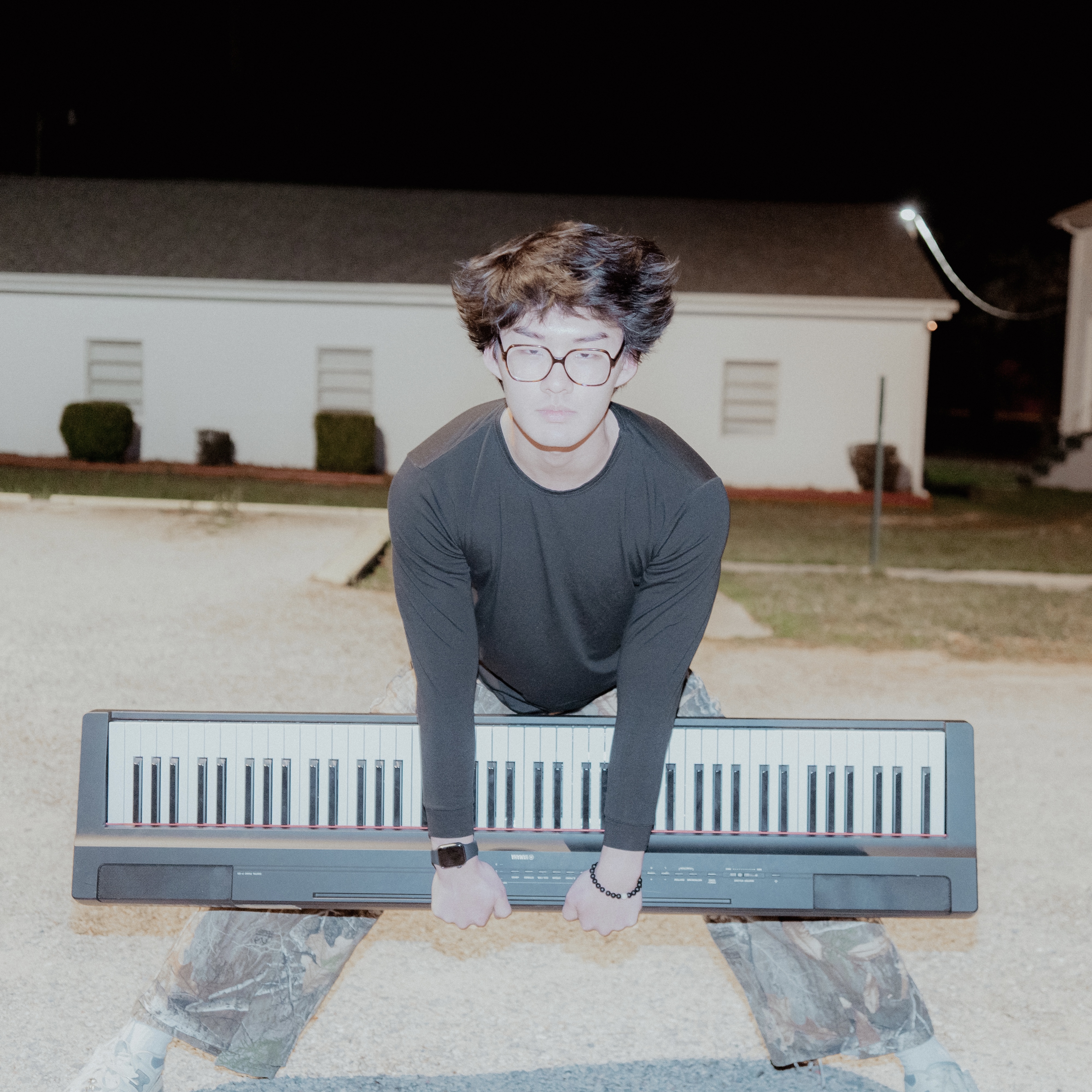 a young Asian man holding a piano