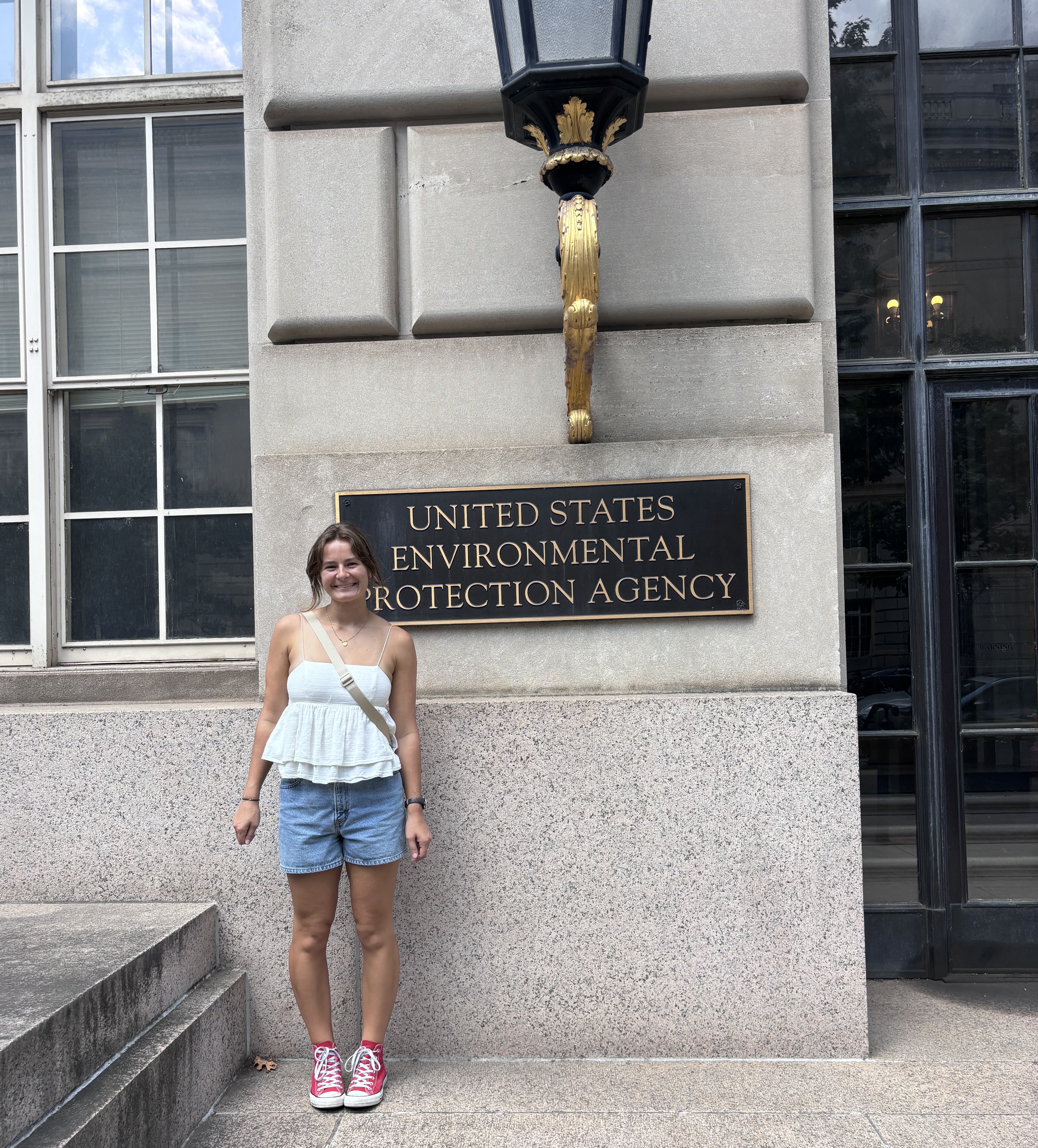 a young white woman stands in front of "US EPA" sign