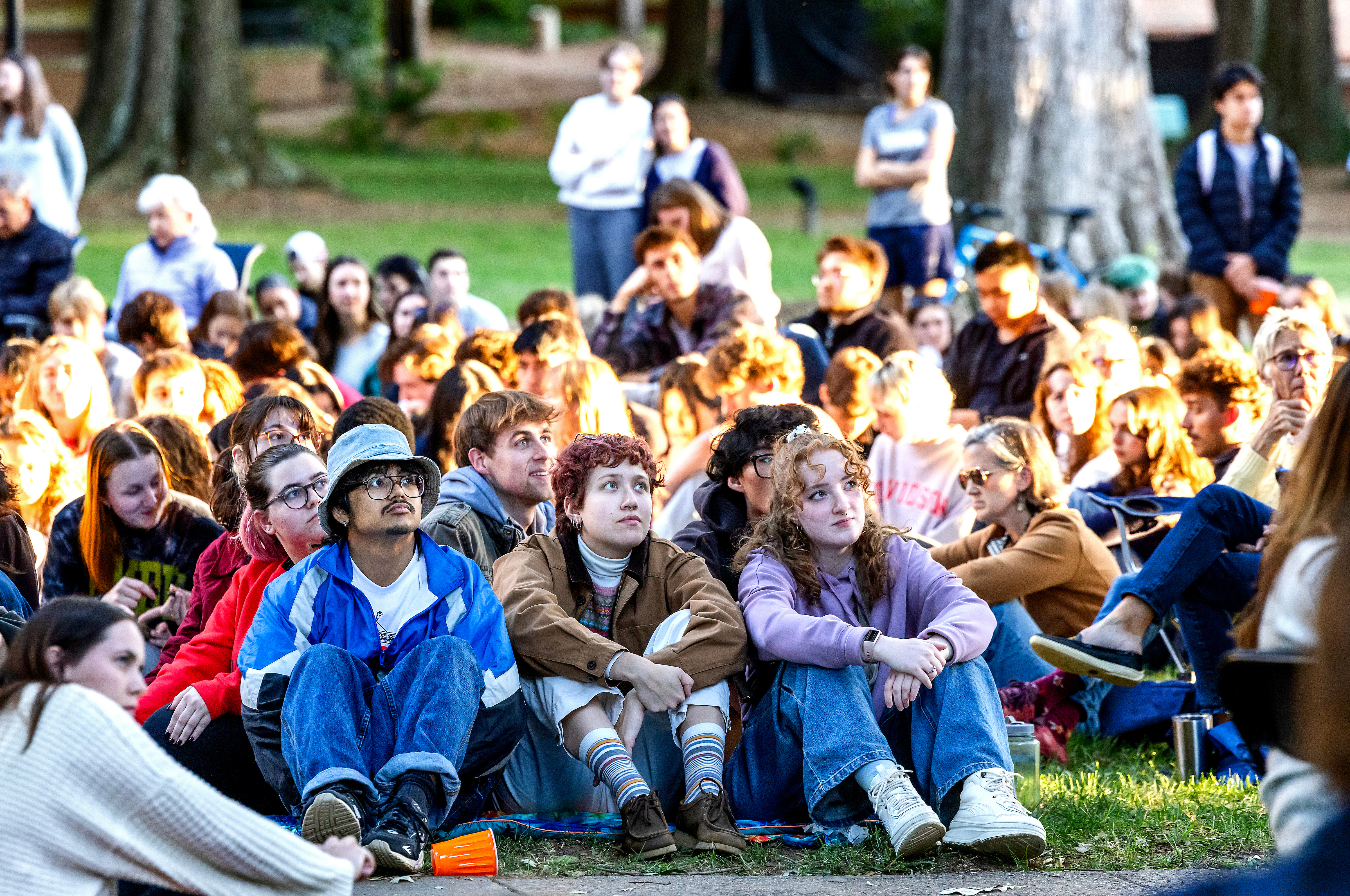 Students sit on the ground, listening intently, at the Phi Eu Debate