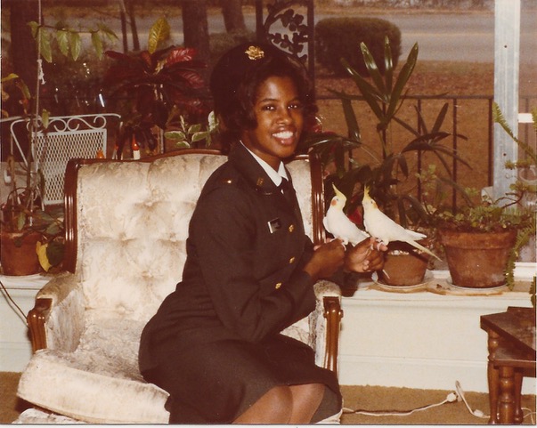 a young Black woman in uniform sitting on a white chair