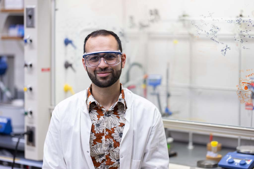 a young man wearing a lab coat over a hawaiian shirt in a lab