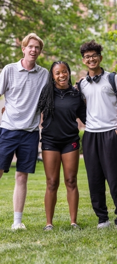 a group of three students stand together smiling