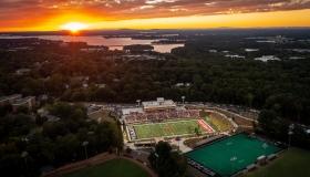 an aerial view of a college campus and lake at sunset