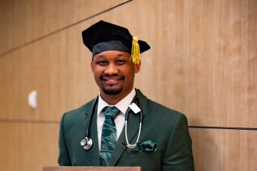 a young man wears a graduation cap and suit and holds a sign that says "I matched Pediatrics at Childrens Hospital of Philadelphia"