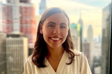 a young white woman smiles in front of a NYC skyline