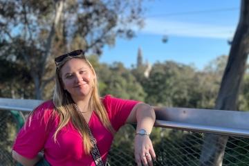 a young white woman stand on an outdoor balcony