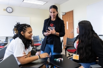 a faculty member talks to two students in a classroom