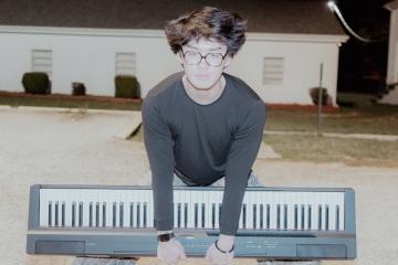 a young Asian man holding a piano