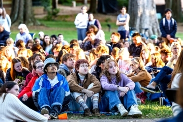 Students sit on the ground, listening intently, at the Phi Eu Debate