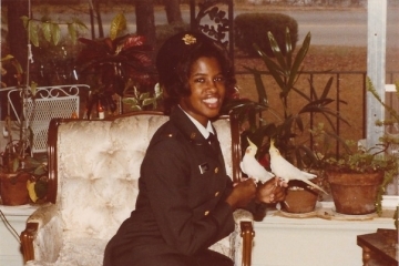 a young Black woman in uniform sitting on a white chair