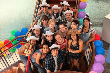 a group of students wearing cowboy hats surrounded by balloons and smiling