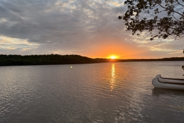 a body of water at sunset with a canoe in the foreground