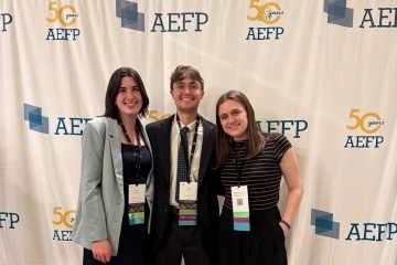 a group of three students in business casual smile together at a conference