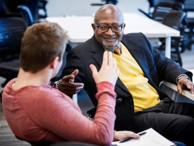 Robert Bullars smiles while a student sitting next to him discusses economics