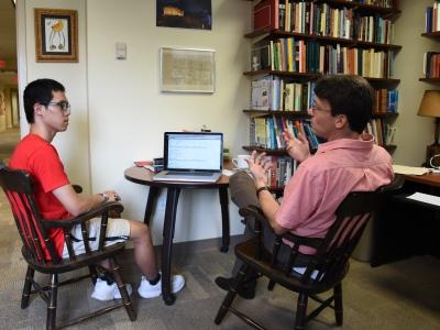 Professor talks to classics student in his office 