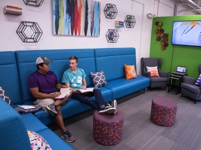 Two students talk while sitting on a couch