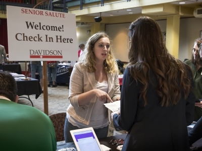 two women speaking in front of sign that says "senior salute"