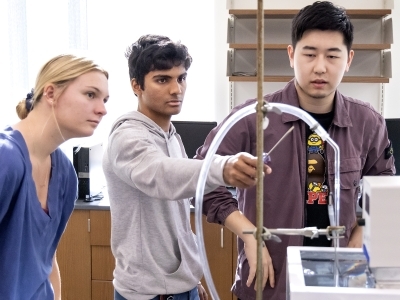 Three students gathered around a chemistry project