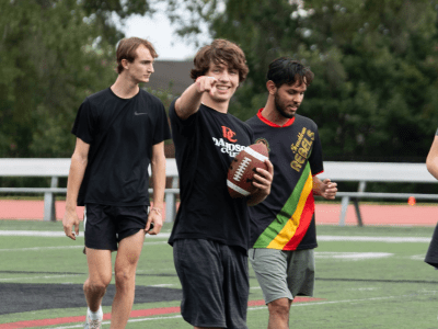 a group of young men holding a football and smiling while standing on a football field