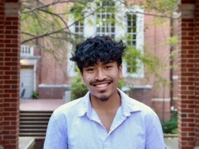 a young man with black hair and facial hair wearing a white button-up