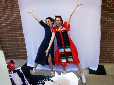 two young women strike a pose in front of a white sheet