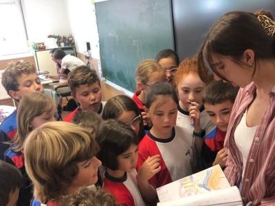 a young woman shows a book to a group of kids