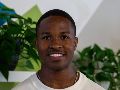 a young Black man smiling wearing a white shirt