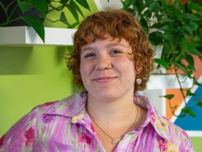 a young white woman with red hair wearing a pink top and smiling