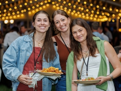 a group of three young women holding plates of food and smiling