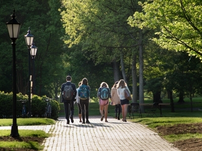 Students walk together on brick path, facing away from the camera