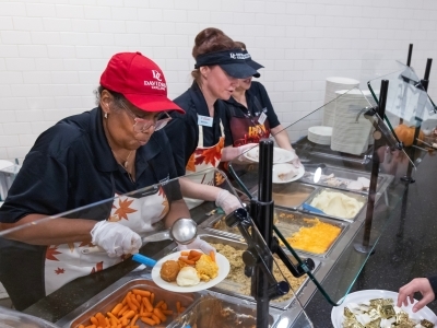 a group of women serve food in a dining hall