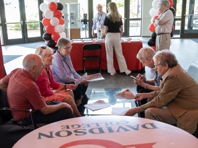 a group of alumni sit around on couches while chatting with each other