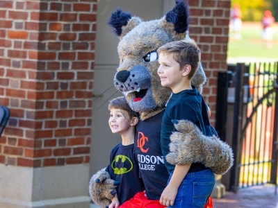 two young kids posing with a cat mascot