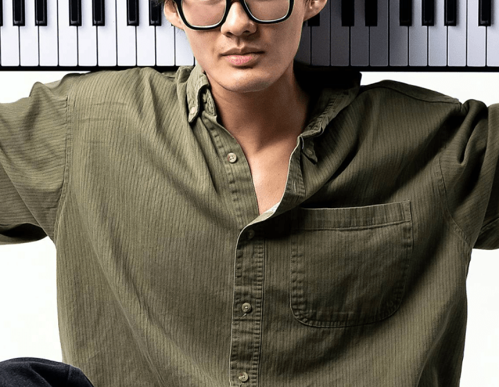 a young Asian man holding a keyboard on his back while sitting cross-legged