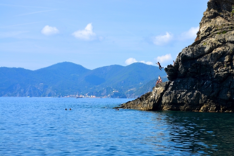 Ocean meets a cliff where a boy cliffdives in Sienna