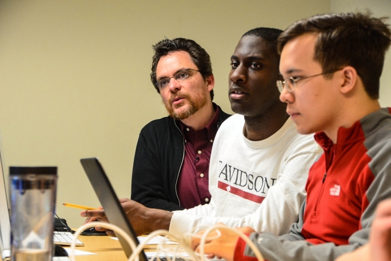 Prof. Chartier sits and talks to two students