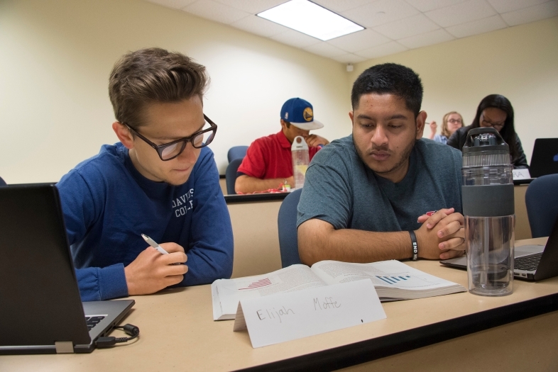 Two students sit next to one another and analyze a text